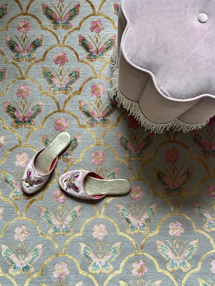 Satin shoes, laid next to a velvet ottoman on an intricate carpet
